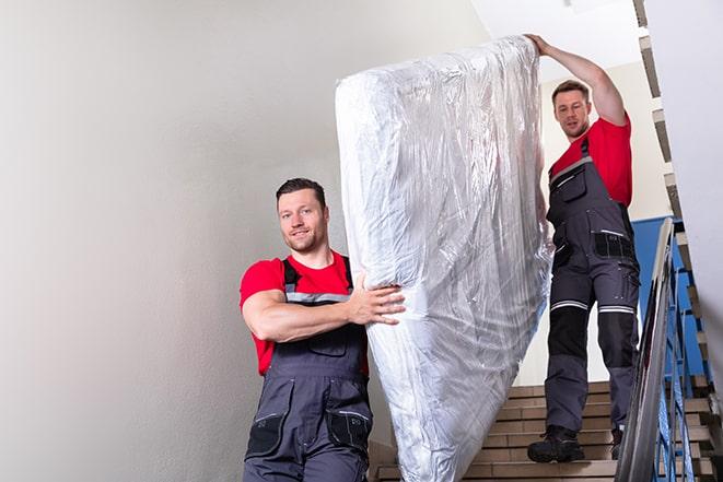 heavy lifting workers transporting a box spring out of a building in Christmas